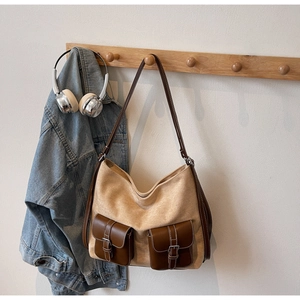 Khaki canvas and brown leather tote bag with double front buckle pockets hanging on hook