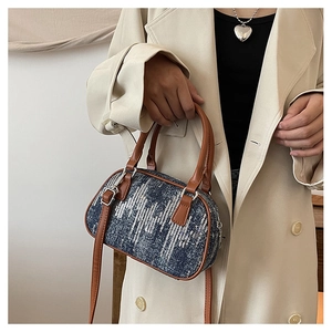 Close-up of sparkling blue denim sequin Boston bag with brown leather handles and silver hardware