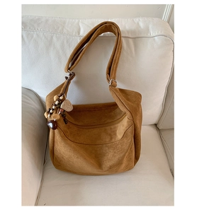 Detail view of brown suede leopard bag featuring wooden beads and heart charm accents