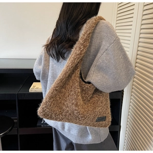 Détail du sac cabas en peluche café montrant la texture douce et l'écusson de marque