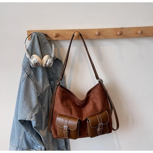 Detailed view of brown suede tote bag with leather pockets and white decorative stitching