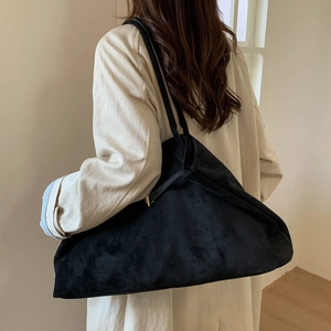 Detailed side view of black suede tote bag with golden metal adjustment buckle and soft drape