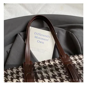 Detail view of houndstooth tote bag fabric with premium brown leather handle