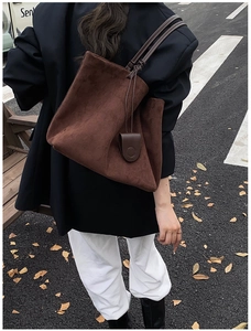 Detail of a dark brown suede tote bag featuring drawstring sides and minimalist straps