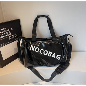 Dettaglio della pelle verniciata nera lucida e logo bianco NOCOBAG sulla borsa sportiva