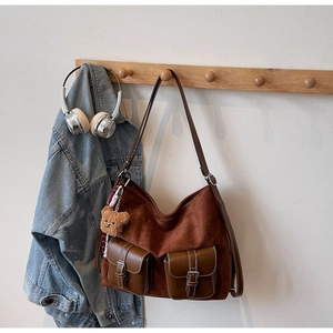 Detail of dark brown suede tote bag featuring front pockets and a cute plush bear charm