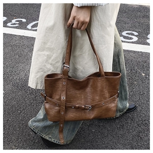 Dettaglio borsa tote vintage in ecopelle marrone con fibbie su modella in strada