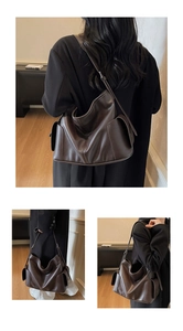 Detail view of large dark brown leather tote bag with side pockets and adjustable strap