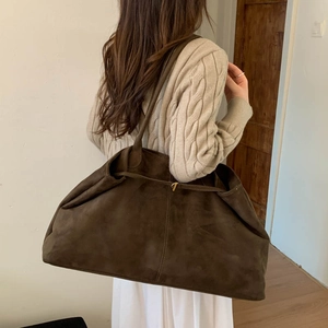 Side view of a large brown faux suede tote bag worn over the shoulder for daily commute