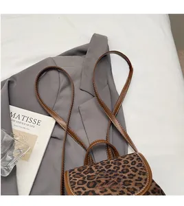 Détail du mini sac à dos léopard avec bordure en cuir marron et surpiqûres blanches