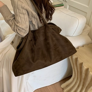 Brown suede tote bag worn by model in a warm, minimalist home interior setting