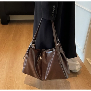 Detail of dark brown tote bag in glossy faux leather with silver metal buckles
