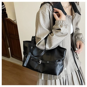 Primo piano dettagliato di una borsa tote nera con occhielli in metallo e cinturini decorativi