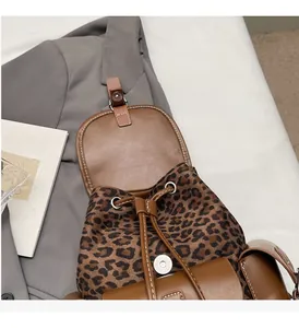 Détail du sac à dos léopard montrant la fermeture à cordon et les boucles dorées