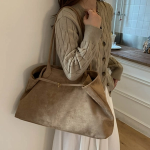 Detailed close-up of large faux suede tote bag with golden buckle and retro texture