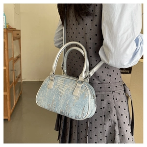 Close-up of light blue denim handbag with silver sequins and metallic top handle