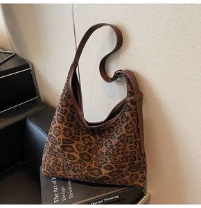 Detailansicht der Leopard-Tragetasche mit braunem Lederriemen, liegend auf einem Buch
