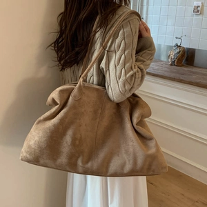 Detail of a large suede tote bag in camel, showing soft drape and slim shoulder straps