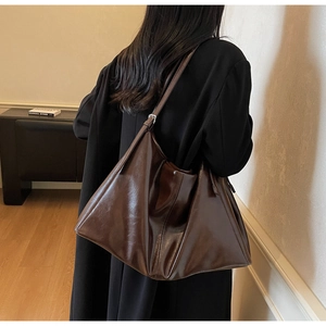 Detail view of large dark brown tote bag showing supple leather texture and adjustable strap