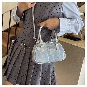 Close-up of a blue sequined denim handbag styled with a grey polka dot dress