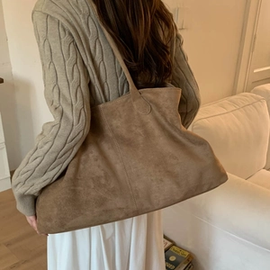 Close-up of brown suede tote bag with vertical stitching details in a cozy lifestyle setting
