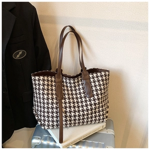 Houndstooth tote bag placed on a silver suitcase showing its spacious capacity and leather straps