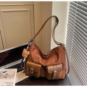 Detail of caramel suede hobo bag with vintage pockets and cute plush bear charm