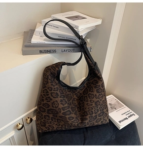 Detail der Hobo-Tasche mit Leopardenmuster und schwarzem Kunstlederriemen auf dem Sofa
