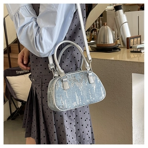 Detailed side view of a sparkling silver sequin handbag with long crossbody strap