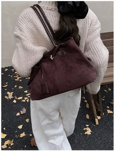 Détail d'un sac cabas en daim bordeaux avec lanières en cuir dans un décor d'automne