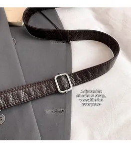 Detail of adjustable dark brown lychee leather shoulder strap with silver buckle