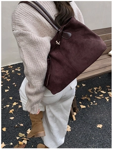 Détail de la texture d'un sac cabas en daim bordeaux foncé avec anses en cuir