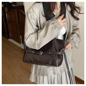 Dettaglio ravvicinato della borsa tote in pelle opaca marrone con fibbia metallica di stile