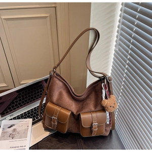 Detail of a brown suede tote bag with leather pockets and a cute teddy bear charm