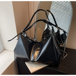 Macro shot of flexible black patent leather tote bag with glossy finish and shoulder strap