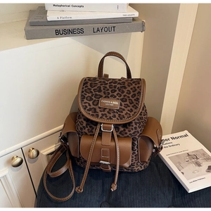 Gros plan du mini sac à dos à imprimé léopard avec détails en cuir sur une chaise bleue