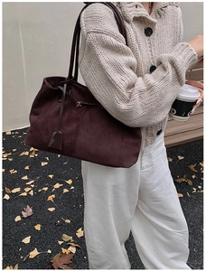 Détail d'un grand sac cabas en daim marron foncé avec de fines lanières dans un décor d'automne