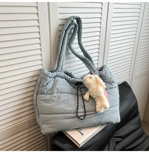 Detailed view of quilted puffer tote bag in light blue-grey with plush rabbit charm