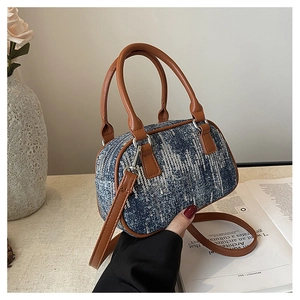 Detailed close-up of blue denim sequin bag with brown leather handles and silver hardware