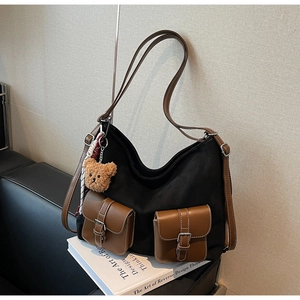 Detail of black canvas hobo bag with brown leather pockets and decorative scarf accessory