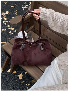 Détail du sac fourre-tout en daim bordeaux sur un banc en bois avec feuilles d'automne