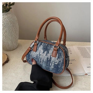 Detailed view of denim texture with white sequins and brown leather straps on the bag