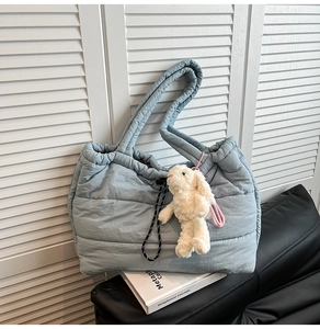 Detail of light blue quilted puffer tote with drawstring closure and plush bunny charm