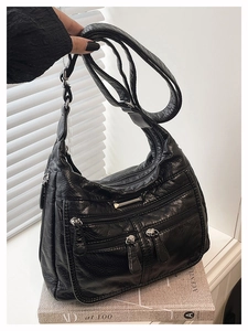 Close-up of black soft leather tote bag showing vintage crinkle texture and silver zippers