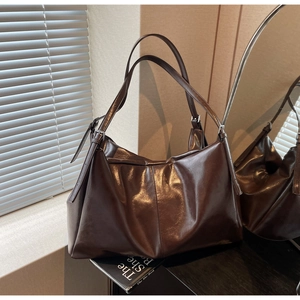 Detail of dark brown tote bag with leather texture and silver buckle in soft lighting