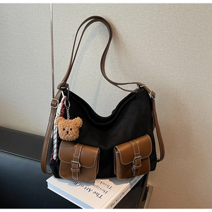 Detail view of stylish tote bag with brown leather pockets and a cute bear charm