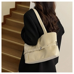 Dettaglio borsa shopper color crema con fibbia argento su una scala in legno moderna