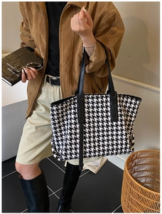 Detail of classic houndstooth tote bag with leather handles in a chic autumn fashion look