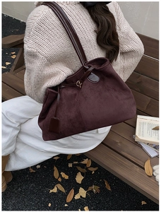 Détail du sac cabas en daim bordeaux avec bandoulière en cuir verni en automne