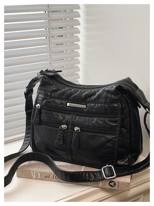 Detail of a vintage black soft leather tote bag showing textured surface and silver zippers